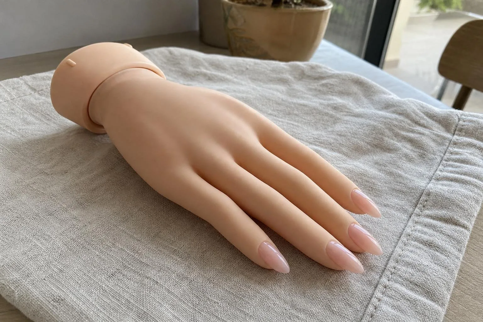 Uñas de gel constructor en una mano de práctica sobre lino