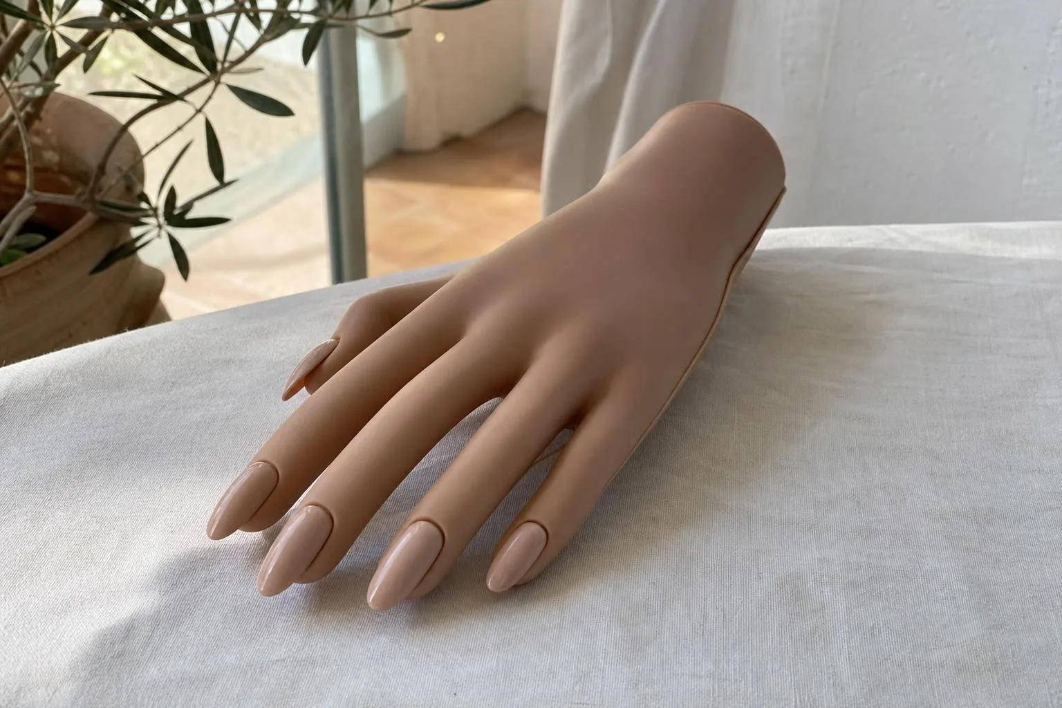 Mano de práctica con uñas Press On nude sobre lino