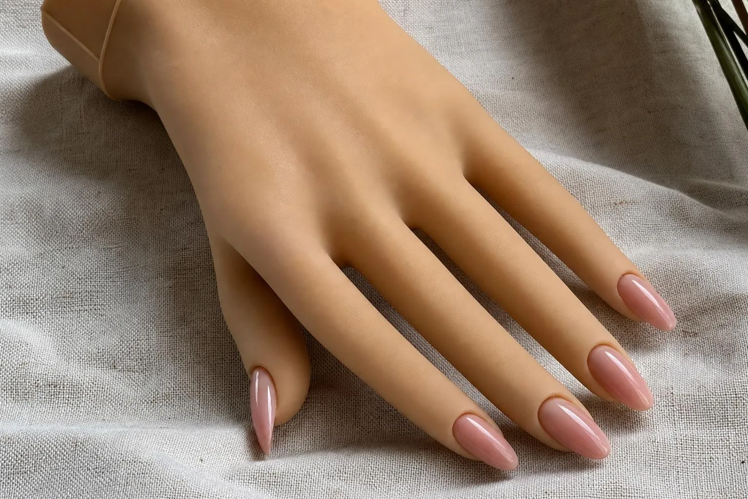 Uñas de gel esculpidas en una mano de práctica sobre lino