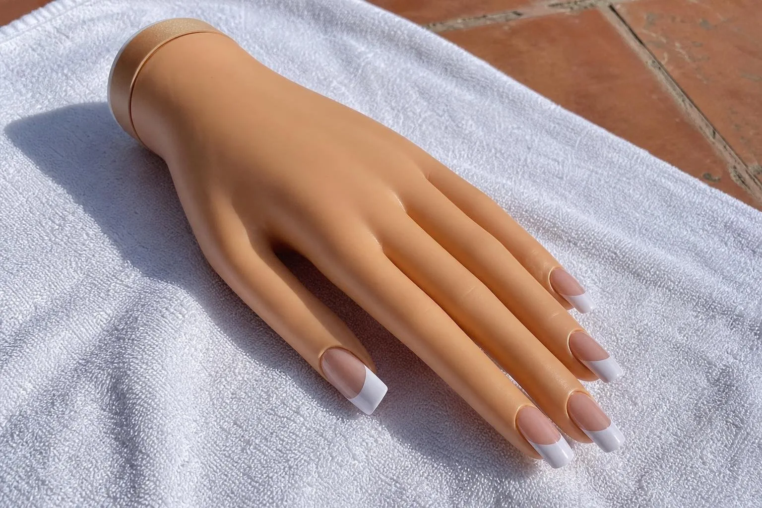Mano de práctica con uñas acrílicas de manicura francesa