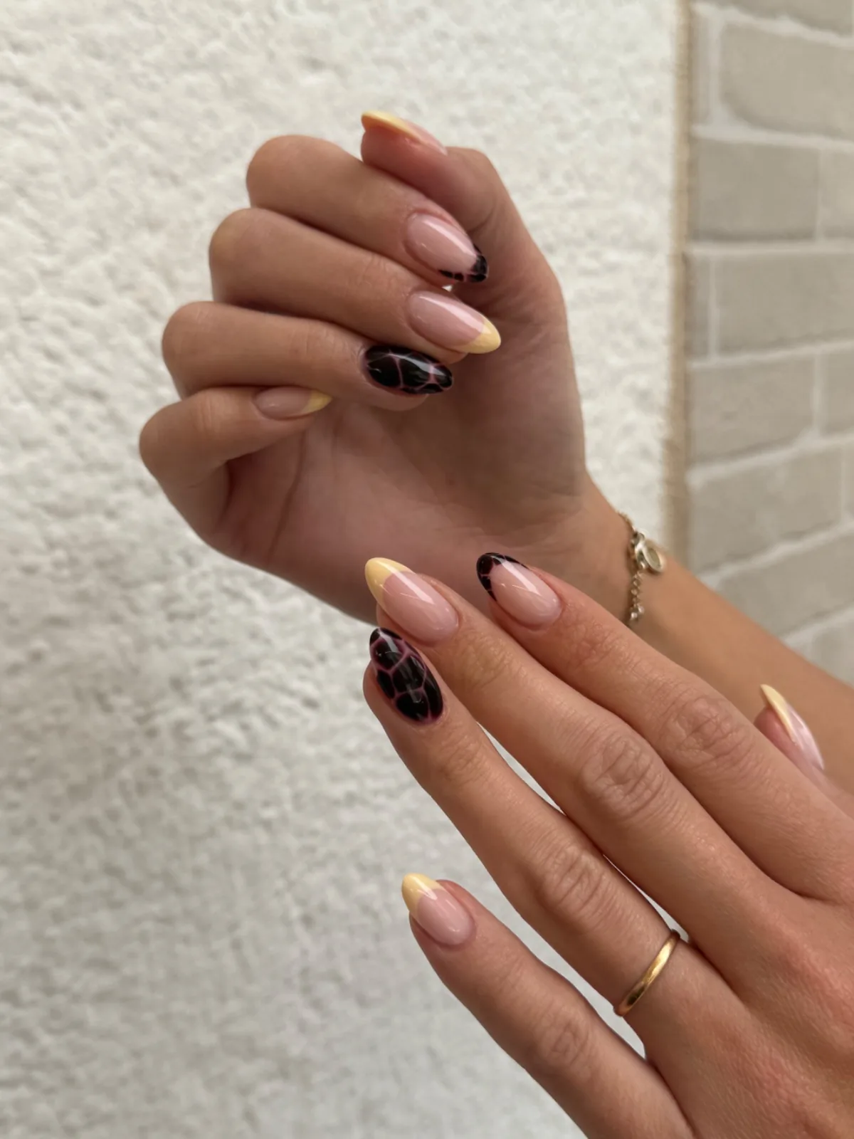 Uñas almendradas nude con punta amarilla y detalles de estampado animal en negro