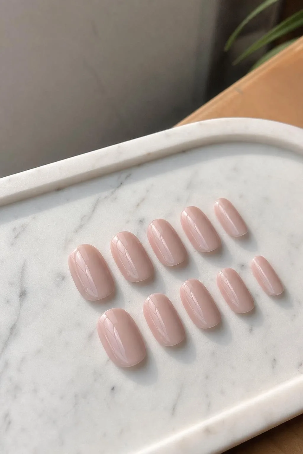 Uñas semipermanentes en tono nude sobre una bandeja de mármol