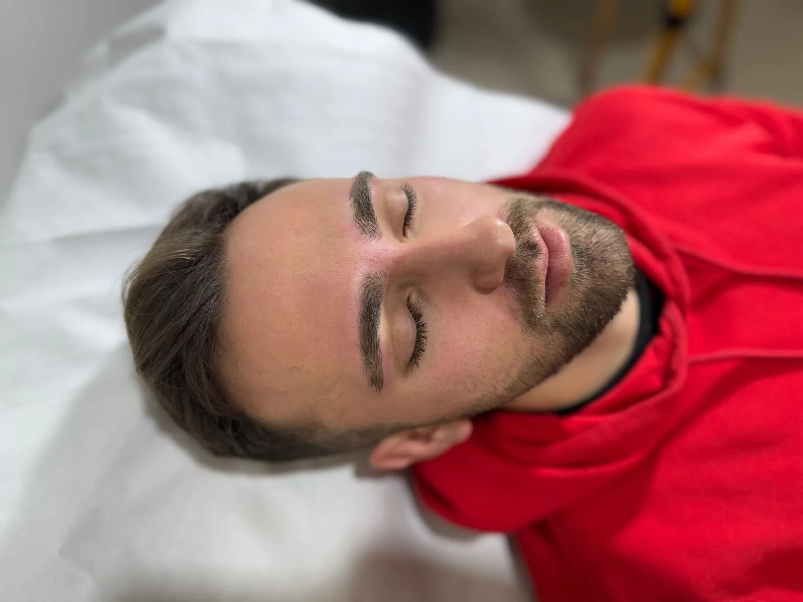Cliente tumbado en la camilla con las cejas peinadas y definidas