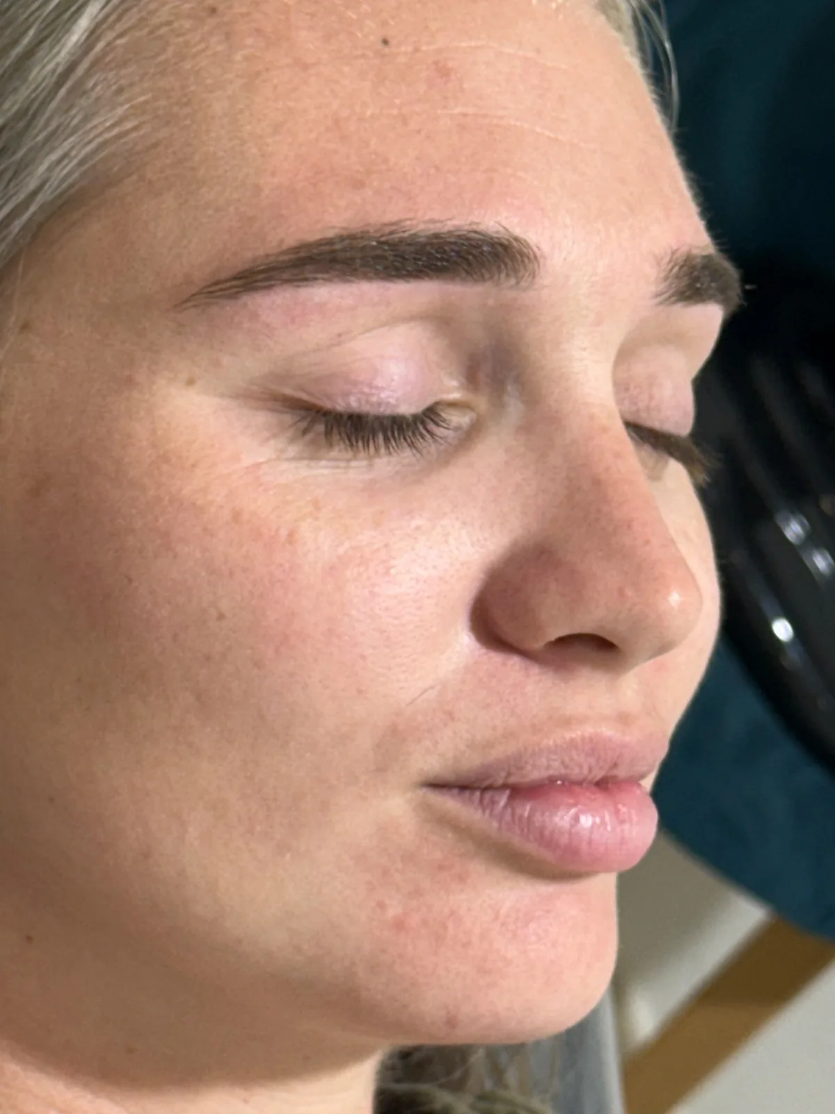 Primer plano de cejas definidas y peinadas en una clienta con los ojos cerrados